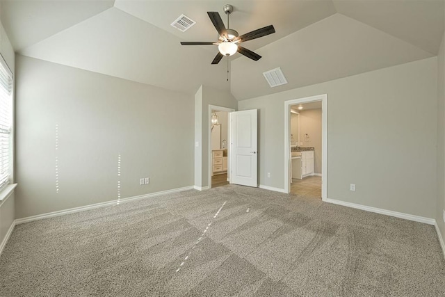 unfurnished bedroom featuring ceiling fan, ensuite bath, light colored carpet, and vaulted ceiling