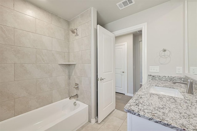 bathroom with tiled shower / bath combo, vanity, and tile patterned floors