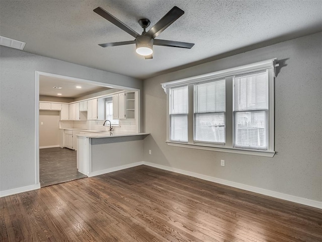 kitchen with white cabinets, tasteful backsplash, sink, kitchen peninsula, and ceiling fan