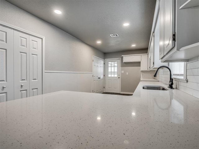 kitchen featuring sink, white cabinetry, and backsplash