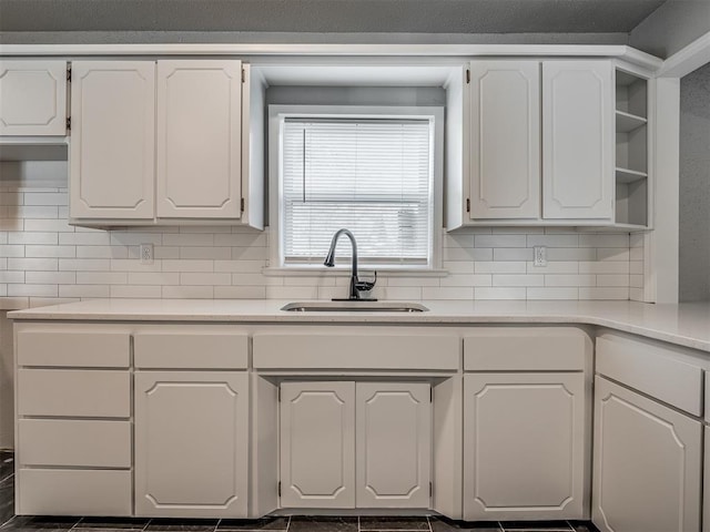 kitchen featuring dark tile patterned flooring, white cabinets, tasteful backsplash, and sink