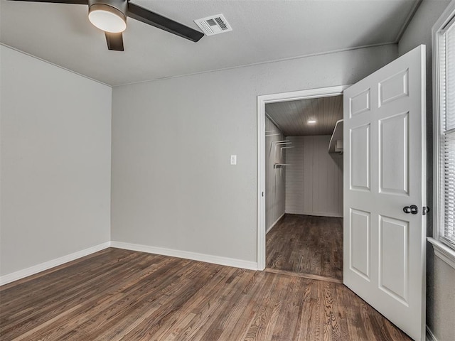 empty room featuring ceiling fan, a wealth of natural light, and dark hardwood / wood-style flooring