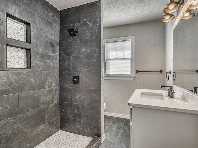 bathroom featuring toilet, vanity, tile patterned flooring, tiled shower, and a textured ceiling