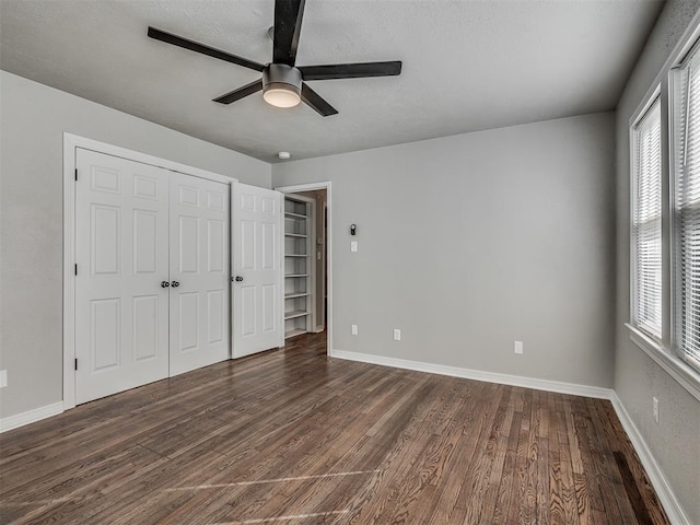 unfurnished bedroom featuring dark wood-type flooring, ceiling fan, and a closet