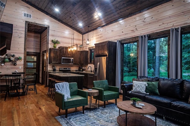 living room featuring wooden walls, high vaulted ceiling, sink, wooden ceiling, and light wood-type flooring