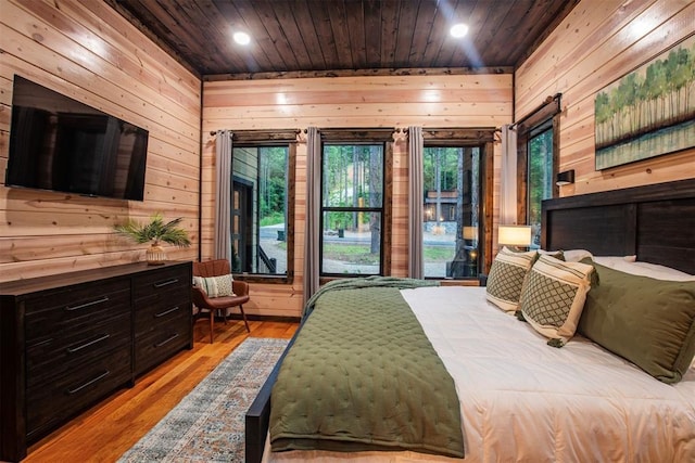 bedroom featuring access to exterior, wooden walls, wooden ceiling, and light hardwood / wood-style floors