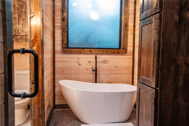 bathroom featuring a washtub and wooden walls