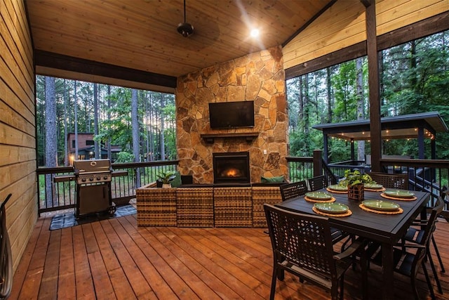 sunroom featuring lofted ceiling, wooden ceiling, and an outdoor stone fireplace