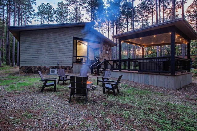 yard at dusk featuring a wooden deck and a fire pit