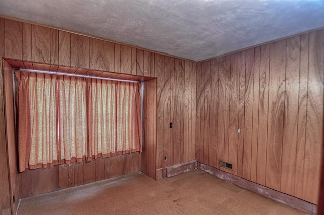 spare room featuring carpet and wood walls