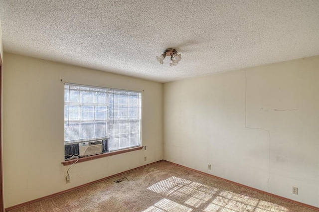 empty room featuring cooling unit, a textured ceiling, and light colored carpet