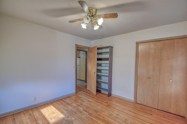 unfurnished bedroom featuring ceiling fan, a closet, white fridge, and light hardwood / wood-style flooring