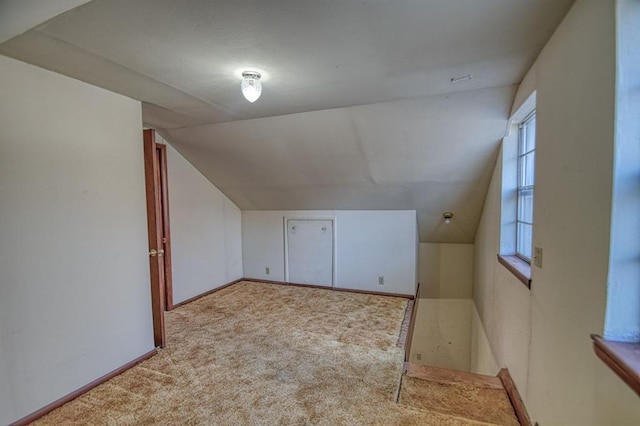 additional living space with vaulted ceiling and light carpet