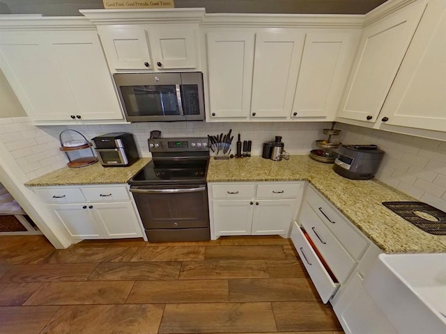 kitchen with white cabinetry, backsplash, and electric range