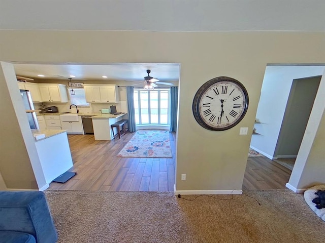 kitchen with ceiling fan, sink, light wood-type flooring, stainless steel appliances, and white cabinets