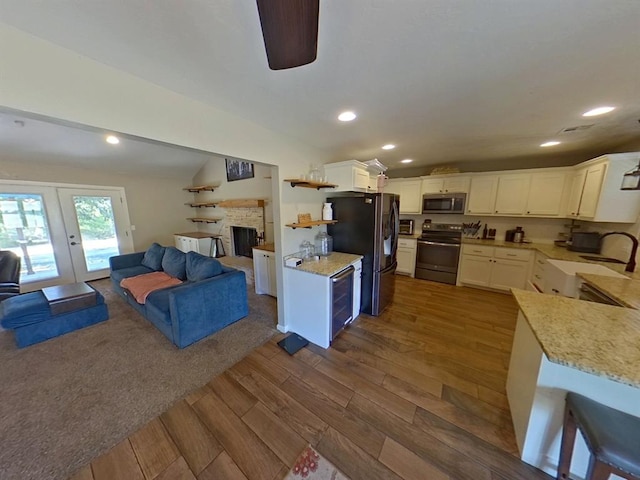 kitchen with appliances with stainless steel finishes, dark hardwood / wood-style floors, french doors, white cabinets, and sink