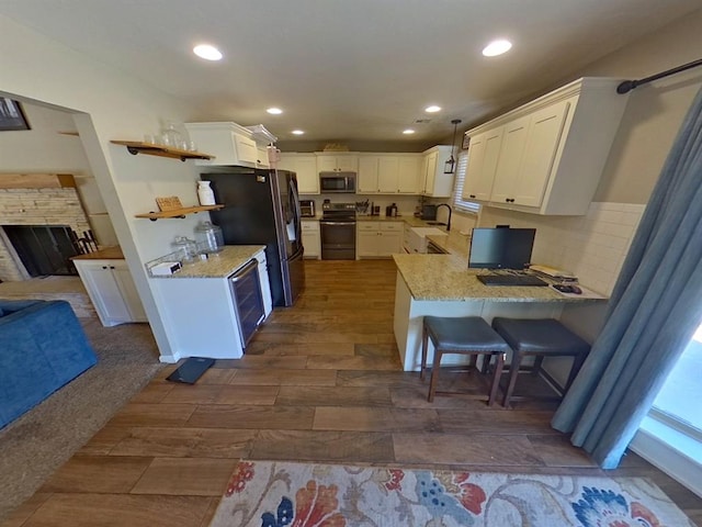 kitchen featuring kitchen peninsula, sink, white cabinetry, hanging light fixtures, and appliances with stainless steel finishes