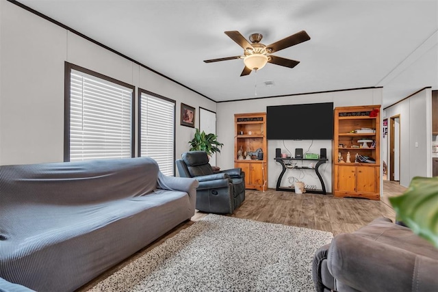 living room with light wood-type flooring, ceiling fan, and crown molding