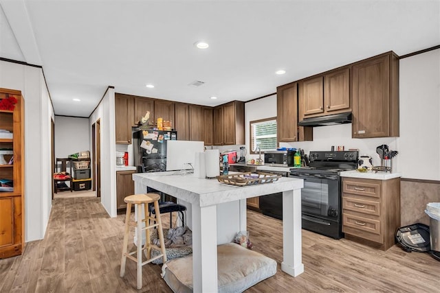 kitchen with light wood-type flooring, dishwasher, ornamental molding, black electric range oven, and a breakfast bar