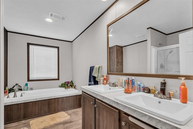 bathroom with wood-type flooring, vanity, ornamental molding, and independent shower and bath