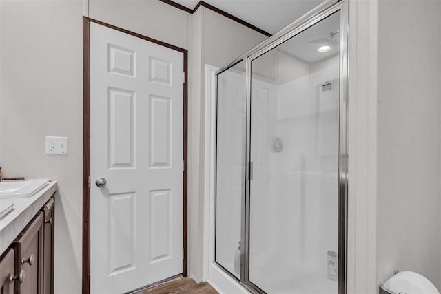 bathroom featuring hardwood / wood-style flooring, walk in shower, crown molding, and vanity