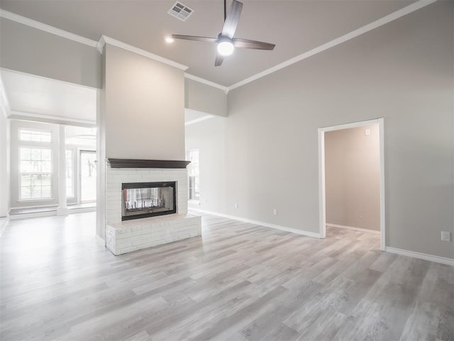 unfurnished living room with ceiling fan, a fireplace, crown molding, and light hardwood / wood-style floors