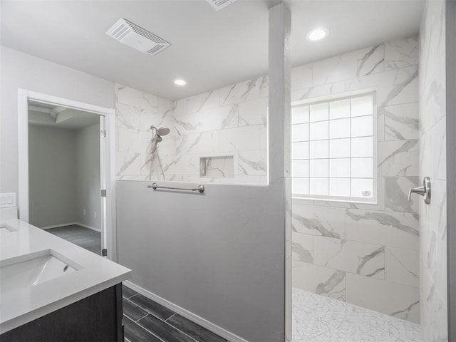 bathroom with vanity and a tile shower