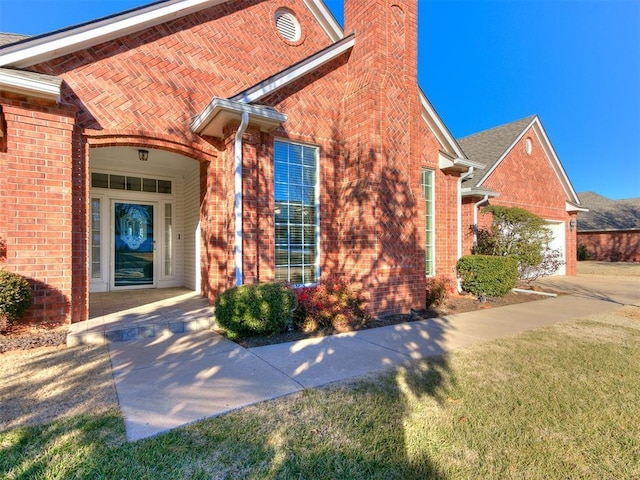 entrance to property featuring a garage and a lawn