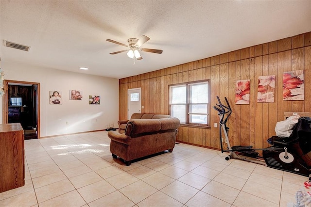 living room with ceiling fan, light tile patterned flooring, and wood walls