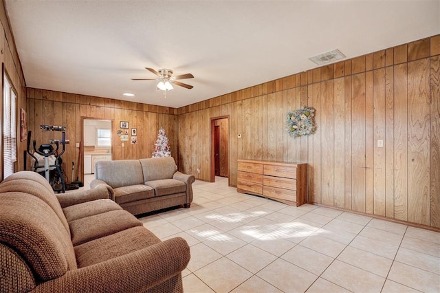 tiled living room featuring ceiling fan and wooden walls