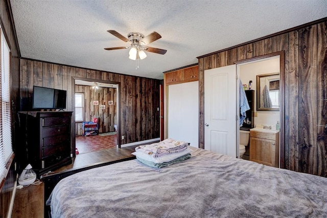 bedroom featuring ceiling fan, a textured ceiling, hardwood / wood-style floors, and wooden walls