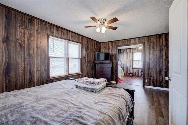 bedroom featuring ceiling fan, a textured ceiling, dark hardwood / wood-style floors, and wooden walls