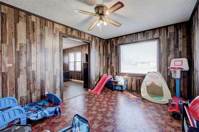 interior space featuring ceiling fan, wooden walls, and a textured ceiling