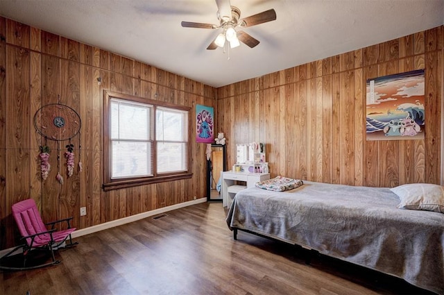 bedroom featuring wood walls, ceiling fan, and hardwood / wood-style flooring