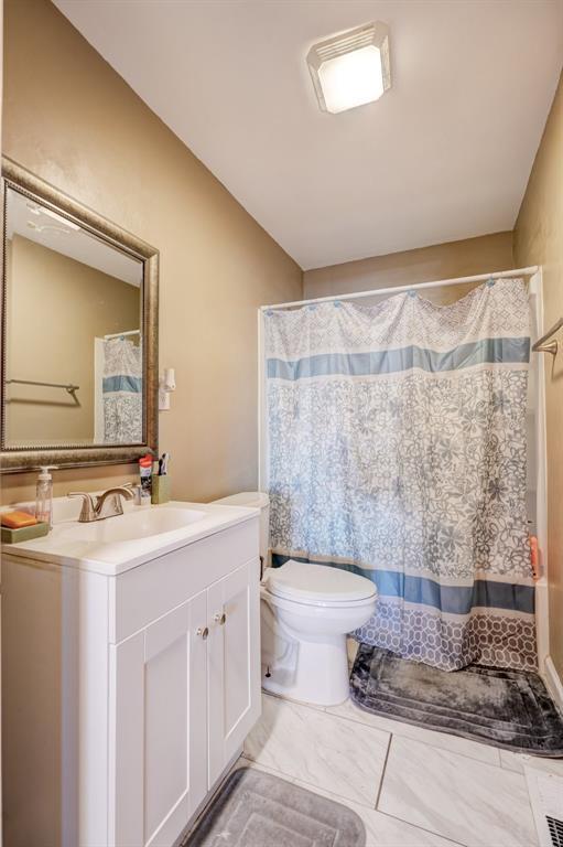 bathroom featuring toilet, vanity, and walk in shower