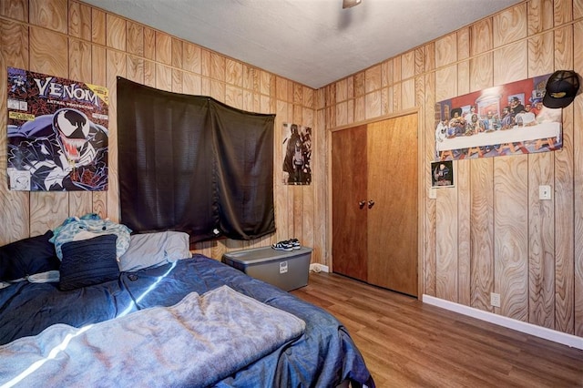 bedroom with wood walls, ceiling fan, a closet, and hardwood / wood-style flooring