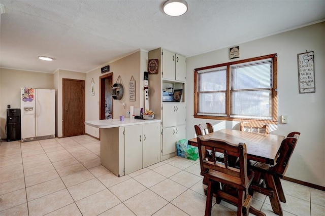 kitchen with white cabinetry, white fridge with ice dispenser, light tile patterned floors, and kitchen peninsula