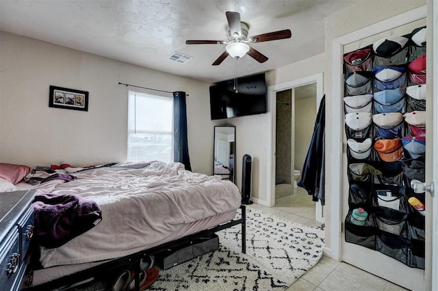 bedroom featuring ceiling fan, light tile patterned floors, and ensuite bath