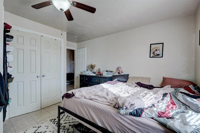 tiled bedroom featuring ceiling fan and a closet