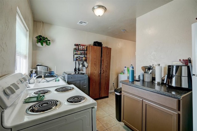 kitchen featuring sink, electric stove, light tile patterned floors, and plenty of natural light