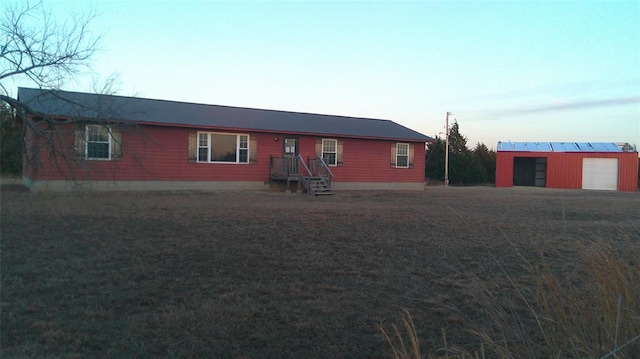 back house at dusk featuring a garage and an outbuilding