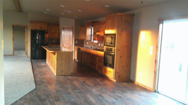 kitchen with black appliances, a kitchen island, a kitchen bar, dark hardwood / wood-style flooring, and sink