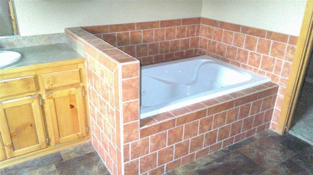 bathroom featuring tiled tub and vanity