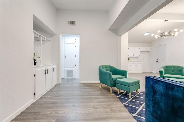 living area with light hardwood / wood-style flooring and a notable chandelier