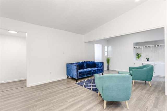 living room featuring lofted ceiling and light hardwood / wood-style flooring