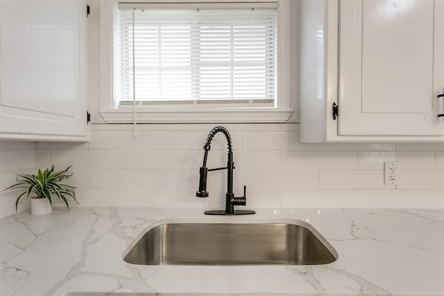 interior details with white cabinets, tasteful backsplash, and sink