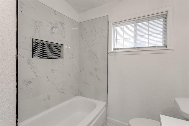 bathroom featuring toilet, a textured ceiling, and tiled shower / bath combo