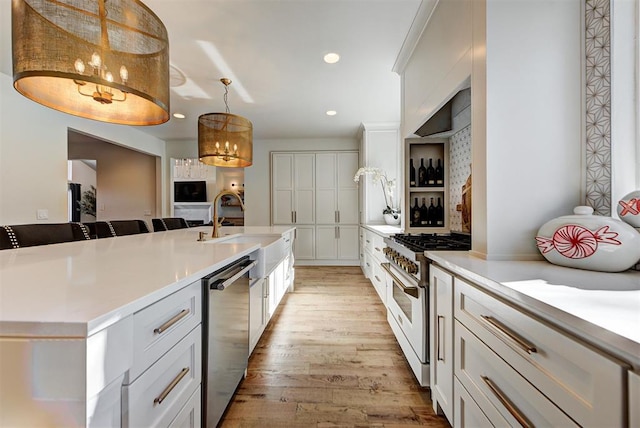 kitchen with sink, dishwasher, white cabinetry, hanging light fixtures, and gas range