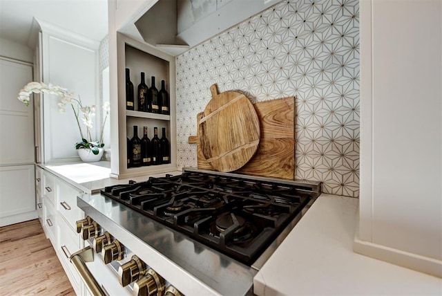 kitchen featuring light hardwood / wood-style floors, stovetop, decorative backsplash, and white cabinets