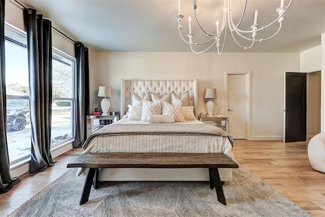 bedroom featuring multiple windows, a notable chandelier, and light hardwood / wood-style flooring